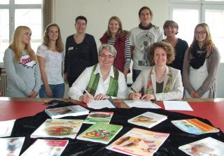 Veronika Czerwinski und Kerstin Kocura (vorne) unterschrieben im Beisein von Kolleginnen und Schülern den Kooperationsvertrag. Foto: SMMP/Hofbauer